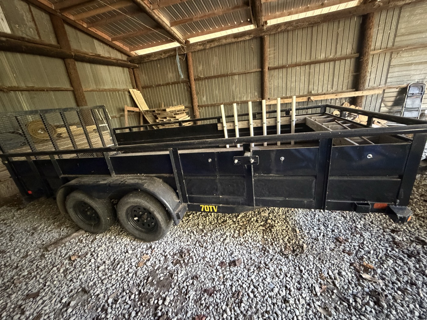 Black Big Tex tandem-axle utility trailer with high steel sides, parked in a barn