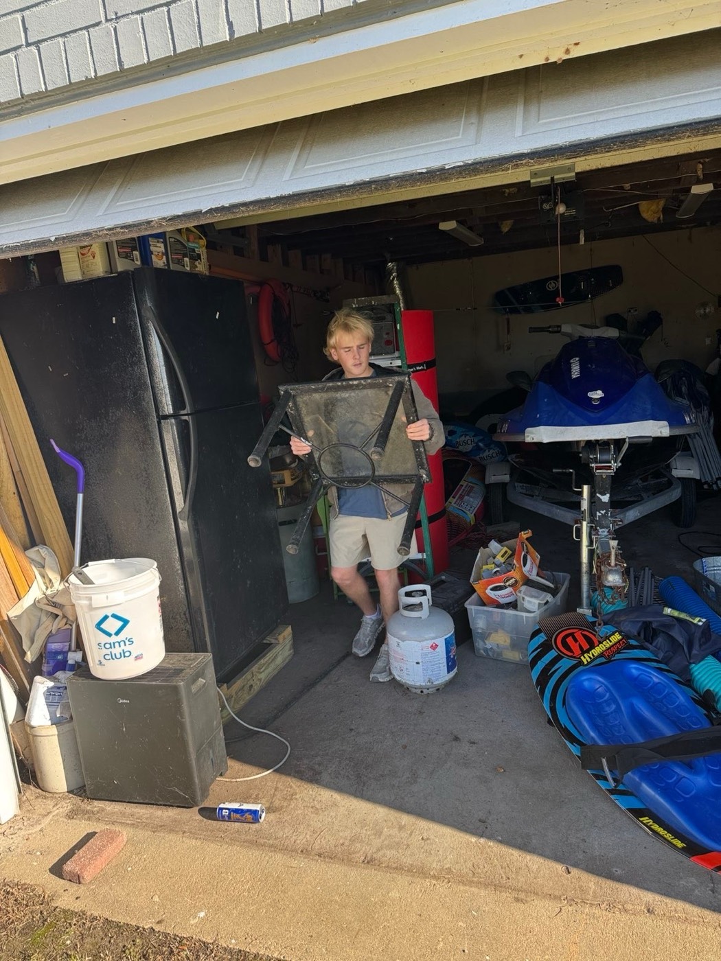 Crew member carrying an old patio table out of a packed garage